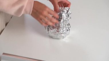 Beyaz mutfak masasındaki genç kadın pasta ya da kurabiye hazırlamak için folyo paketini hamurla açıyor. Evde yemek pişirme malzemesi kavramı, aşçılık hobisi