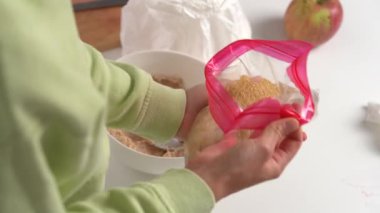 Genç bir kadının mutfak masasındaki hamura kaşık dolusu kahverengi kamış şekeri kattığı fotoğraf. Ev yapımı kavramı, tarife göre pasta yapmak, kurabiyeler, malzemeler hazırlamak.