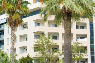 Arnavutluk 'ta deniz kıyısı yakınlarında palmiye ağaçları bulunan Akdeniz tarzı modern minimalist apartmanlar. Yabancı gayrimenkul kavramı, dijital göçebeler, tatil köyündeki kiralık daireler.