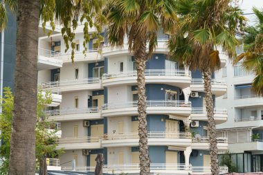 Arnavutluk 'ta deniz kıyısı yakınlarında palmiye ağaçları bulunan Akdeniz tarzı modern minimalist apartmanlar. Yabancı gayrimenkul kavramı, dijital göçebeler, tatil köyündeki kiralık daireler.