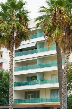 Arnavutluk 'ta deniz kıyısı yakınlarında palmiye ağaçları bulunan Akdeniz tarzı modern minimalist apartmanlar. Yabancı gayrimenkul kavramı, dijital göçebeler, tatil köyündeki kiralık daireler.