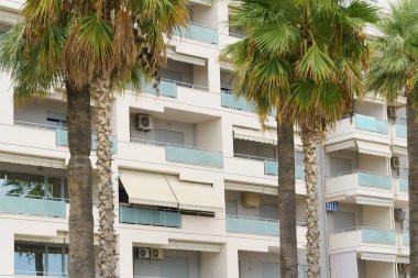 Arnavutluk 'ta deniz kıyısı yakınlarında palmiye ağaçları bulunan Akdeniz tarzı modern minimalist apartmanlar. Yabancı gayrimenkul kavramı, dijital göçebeler, tatil köyündeki kiralık daireler.