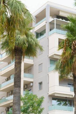 Arnavutluk 'ta deniz kıyısı yakınlarında palmiye ağaçları bulunan Akdeniz tarzı modern minimalist apartmanlar. Yabancı gayrimenkul kavramı, dijital göçebeler, tatil köyündeki kiralık daireler.