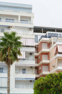 Arnavutluk 'ta deniz kıyısı yakınlarında palmiye ağaçları bulunan Akdeniz tarzı modern minimalist apartmanlar. Yabancı gayrimenkul kavramı, dijital göçebeler, tatil köyündeki kiralık daireler.