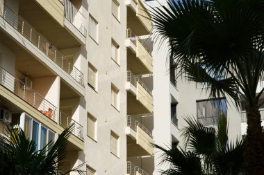 Arnavutluk 'ta deniz kıyısı yakınlarında palmiye ağaçları bulunan Akdeniz tarzı modern minimalist apartmanlar. Yabancı gayrimenkul kavramı, dijital göçebeler, tatil köyündeki kiralık daireler.