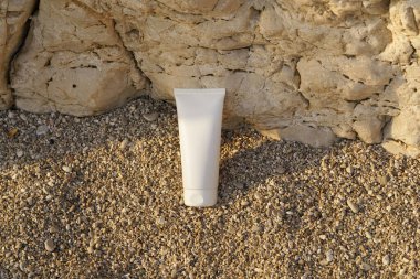 Kayadan bir arka planda küçük bir çakıl taşı üzerinde beyaz bir krem tüpünün üst görüntüsü. Güzellik, vücut ve yüz bakım ürünleri kavramı. Tasarımın için resim