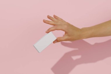 Pembe izole edilmiş arka planda beyaz model kutusunu tutan bir kadın. Güzellik, şekerleme ya da sağlık ürünleri, ambalaj ve markalaşma için reklam ve sunum kavramı. Tasarımınız için şablon