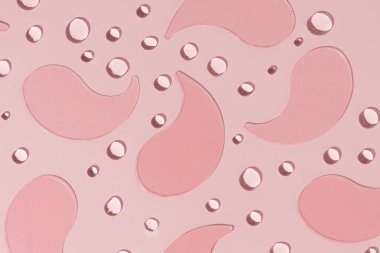 Pembe izole edilmiş arka planda pembe hidrojel göz bantları ve damla dokusu. Göz altı, güzellik rutini ve deri sağlığı konseptini nemlendirmek ve gençleştirmek için tasarlandı..