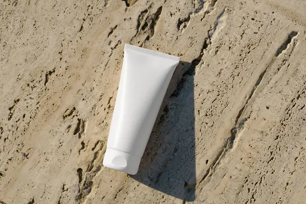 Kayalık sahil şeridinde temiz beyaz bir boru modeli. Güneş kremi, yatıştırıcı yüz kremi, cilt bakımı veya güzellik ürünleri paketleme tasarımı için ideal bir sunum.