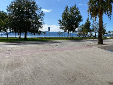 Arnavut kentinde mavi deniz ve yeşil bitki örtüsüne karşı asfalt yol manzarası. Akdeniz 'de tatil ve dinlenme kavramı. Makalen için fotoğraf