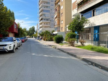 Vlora, Arnavutluk - 16 Ocak 2025: Arnavutluk sokaklarında arabalar, şehir binaları ve sıcak bitki örtüsü çekildi. Akdeniz atmosferi editoryal illüstrasyon ya da seyahat hikayeleri için harika