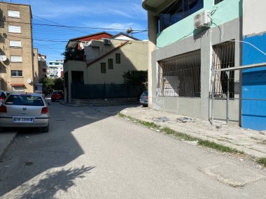 Vlora, Arnavutluk - 16 Ocak 2025: Arnavutluk 'ta güneş ışığı, binalar ve sokak trafiği olan bir Akdeniz sokak sahnesi. Yaratıcı görsel kullanım için yerel kültür ve şehir cazibesini yakalar.