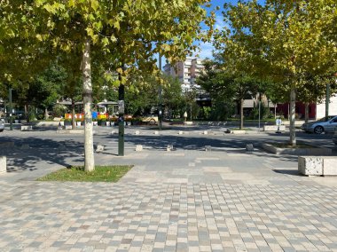 Vlora, Arnavutluk - 16 Ocak 2025: Arabaları, çok katlı evleri ve santralleri olan tipik bir Arnavut kasaba yolu. Akdeniz yaşam tarzı görselleri, tasarım projeleri ya da başyazılar için uygun.