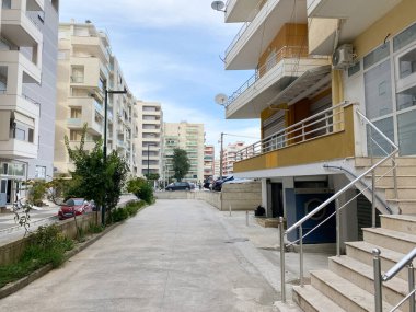 Arnavutluk 'un Vlora kenti - 16 Ocak 2025: Binalar ve tropikal görünümlü bitkilerle dolu güzel bir Arnavut caddesi. Sıcaklığı, sadeliği ve güney yaşam tarzını ifade etmek için harika bir görüntü..