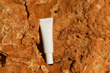 Sahildeki kireç taşının üzerinde beyaz bir serum ya da yüz kremi tüpü. Doğal cilt bakım ürünleri, güzellik, estetik, spa ve rahatlama kavramı