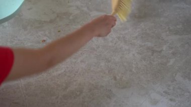 Kadın mutfak masasını küçük el fırçası ve faraşla temizliyor, toprak ve kırıntıları temizliyor. Görüntüler, temizlik ve ürün temaları için uygun ev işleri, organizasyon ve yaşam tarzını temsil ediyor..