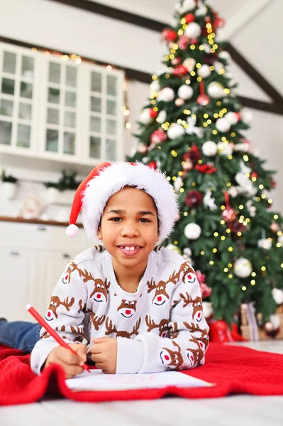 Child Boy Santa Hat Lying Plaid Smiles Dreamily Writes Letter — Stock Photo, Image