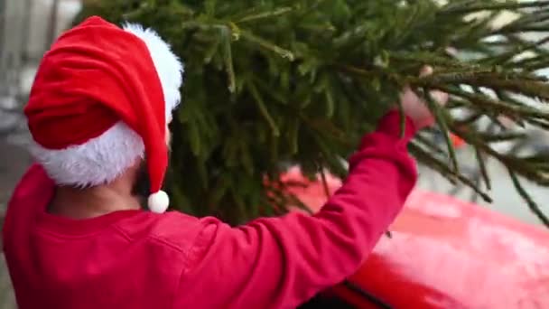 Jovem Com Uma Camisola Vermelha Chapéu Papai Noel Está Amarrando — Vídeo de Stock