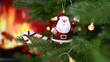 Noel oyuncağı. Noel ağacındaki Noel Baba figürü şöminedeki yanan ateşin arka planına karşı..