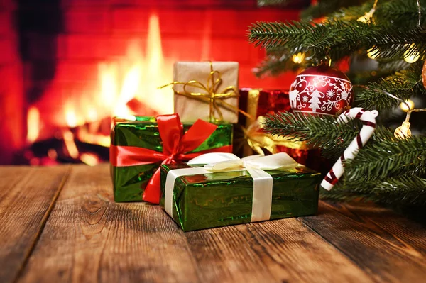 stock image a lot of boxes with Christmas gifts on a wooden table against the background of a Christmas tree and a fireplace.