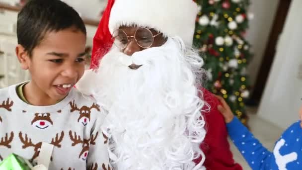 非裔美国人圣诞老人和孩子们一起玩耍 在圣诞树下玩得很开心 — 图库视频影像