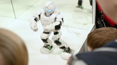 Rostov-on-Don, Russian Federation - December 27, 2022. Children watch a dancing robot at a robotics exhibition.