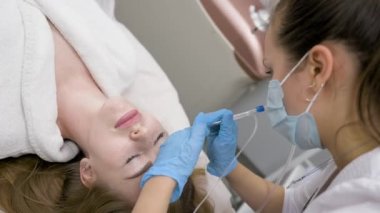 cosmetic procedure gas-liquid peeling - rejuvenation and regeneration of the skin using a jet consisting of oxygen and liquid. The cosmetologist holds an applicator with oxygen and carbon dioxide in