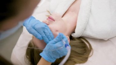 cosmetic procedure gas-liquid peeling - rejuvenation and regeneration of the skin using a jet consisting of oxygen and liquid. The cosmetologist holds an applicator with oxygen and carbon dioxide in