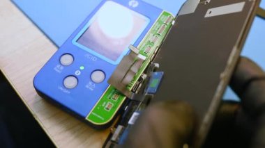 Kharkiv, Ukrayna - 2 Şubat 2022: Usta iPhone 'u söker ve onarır ve programcıdaki ekrana bilgi yazar.
