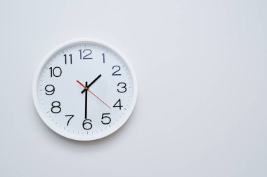beautiful white wall clock close-up on a white wall shows the time 13.30
