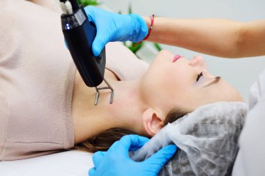 A cosmetologist uses a CO2 fractional ablative laser to rejuvenate the skin and remove scars in a modern cosmetic beauty clinic.