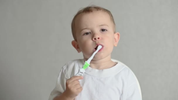 Das Kind Putzt Seine Zähne Mit Einer Zahnbürste Auf Grauem — Stockvideo