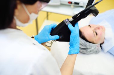 A cosmetologist uses a CO2 fractional ablative laser to rejuvenate the skin and remove scars in a modern cosmetic beauty clinic.