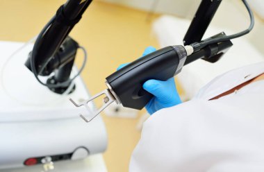 The cosmetologist holds a CO2 fractional ablative laser for skin rejuvenation and scar removal in his hands and prepares for the procedure.Laser cosmetology
