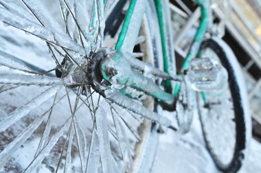 Şiddetli bir soğukta kışın arka planda buzun üzerinde buzlu yeşil bir motorsiklet..