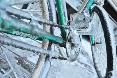 Şiddetli bir soğukta kışın arka planda buzun üzerinde buzlu yeşil bir motorsiklet..