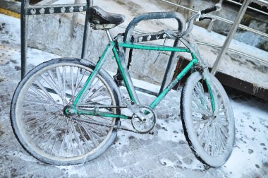 Şiddetli bir soğukta kışın arka planda buzun üzerinde buzlu yeşil bir motorsiklet..