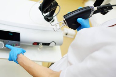 The cosmetologist holds a CO2 fractional ablative laser for skin rejuvenation and scar removal in his hands and prepares for the procedure.Laser cosmetology