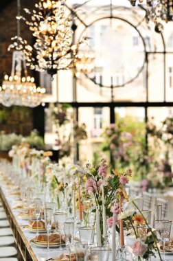 Çiçeklerin zarif dekoru ve düğün masasında zarif bir servis. Modern düğün dekorasyonu