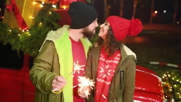 恋人のカップル 男性と女性はクリスマスの贈り物や雪を背景にキスをし 彼らの手に輝きを保持 — ストック動画