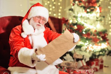 Geleneksel kırmızı beyaz takım elbiseli ve yuvarlak gözlüklü gerçek beyaz sakallı Noel Baba elinde çocukların istekleri karşısında uzun bir liste tutarken şaşırıyor.