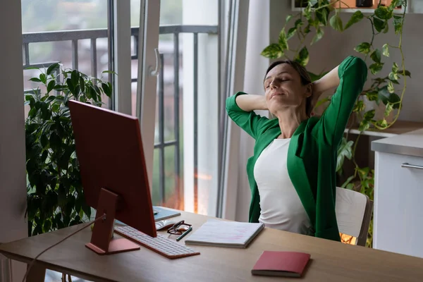 成功したポーランドのビジネス女性は困難なプロジェクトを完了し 仕事をした後に手を伸ばす 専門家の女の子は 会社のためにリモートで働いて自宅のオフィスでコンピュータとテーブルに座っている — ストック写真