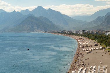 Antalya plajlarında güneşlenen ve dağların eteklerinde yer alan Konyaalti tatil beldesi olan güneşli Türk kıyıları. Türkiye 'nin sıcak yaz kıyı şeridi ve kuadkopterden deniz manzaralı otel binaları