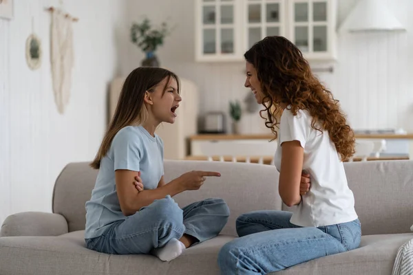 母亲和十几岁的女儿在家里坐在沙发上互相争论 压力很大的母亲试图处理青少年的行为 父母处理青春期的问题 — 图库照片