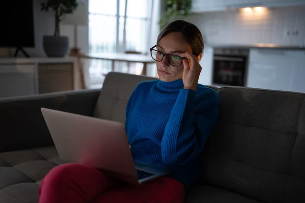 ガラスのノートパソコンの画面を見ての高価なビジネス女性はソファの上に座っている 思考の若い女性は 困難な研究プロジェクトに取り組んで 電子メールを読む 戦略を熟考 オンライン教育のウェビナーを見る — ストック写真