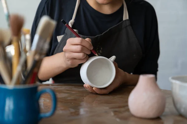 女工匠在工作室里创作了新的杰作 用白色杯子勾画出了未来的图案 女主人想用铅笔粉刷厨房 用粉刷过的泥巴来画一些有趣的图案 — 图库照片
