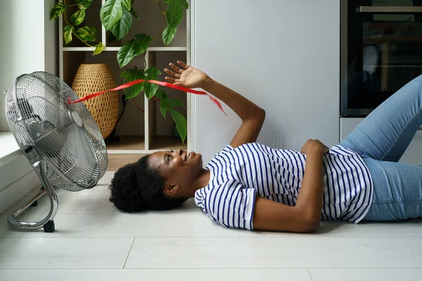 Счастливая Молодая Африканка Лежащая Полу Наслаждающаяся Потоком Воздуха Переносного Электрического — стоковое фото
