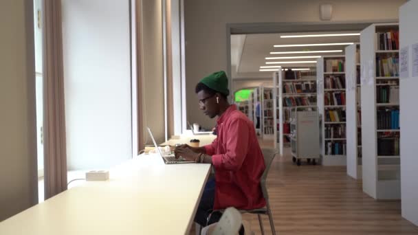アフリカの学生は 近代的な図書館のラップトップコンピュータとテーブルに座って 今後の大学試験の準備中に疲れている 疲れ切った黒人がオンラインで働いている 勉強とストレス 試験前の不安 — ストック動画