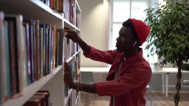 Африканський Гіпстер Шукає Книгу Університетській Бібліотеці Молодий Чорний Чоловік Бере — стокове відео