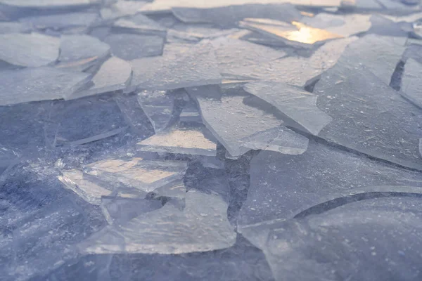 stock image Closeup pieces of cracked ice over body of water or river frozen in cold weather after winter frosts. Broken ice crust covering lake or puddle on city street with glare from rays of morning sun